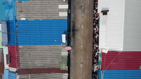 aerial top down view of train passing mae klong railway market, thailand