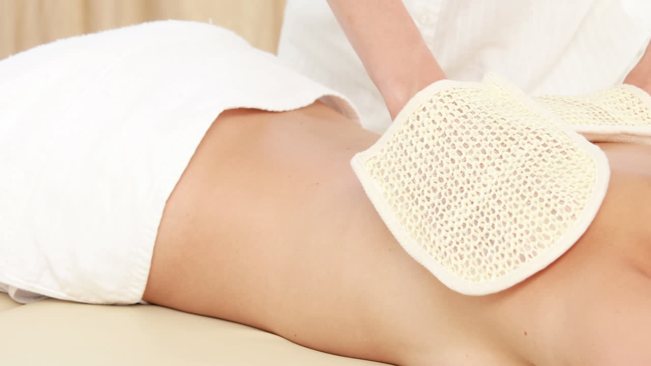 Terapista che massaggia la schiena di una donna con guanti riscaldati