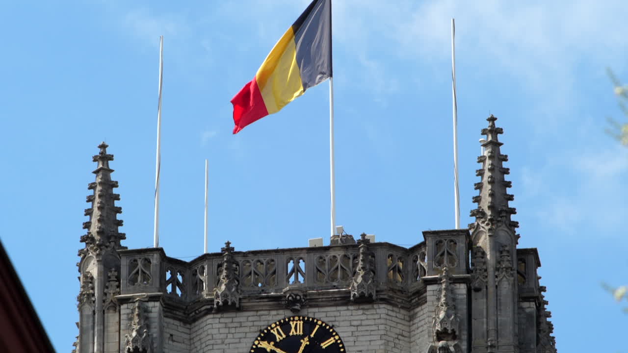 bandera bélgica sobrevolando la torre del reloj de la basílica de tongeren