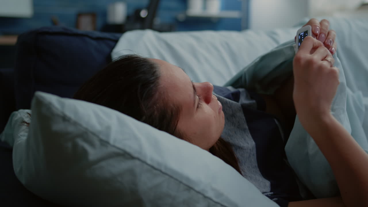 Close up of ill person with oximeter on finger laying on sofa