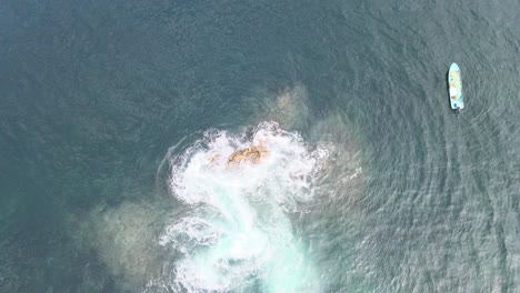 Jib-up-above-rocks-in-the-ocean,-with-two-boats