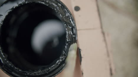 perspectiva única de sumergir un pequeño pincel en una lata llena de barniz negro