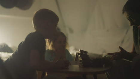 el niño pequeño jugando con la madre y la hermana accidentalmente deja caer toda la torre sobre la mesa. la madre y los niños se sorprenden con el final del juego y cubren la boca. noche de juego de mesa familiar