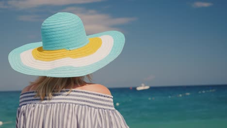 una mujer con un sombrero mira el mar azul. concepto de vacaciones de sueño