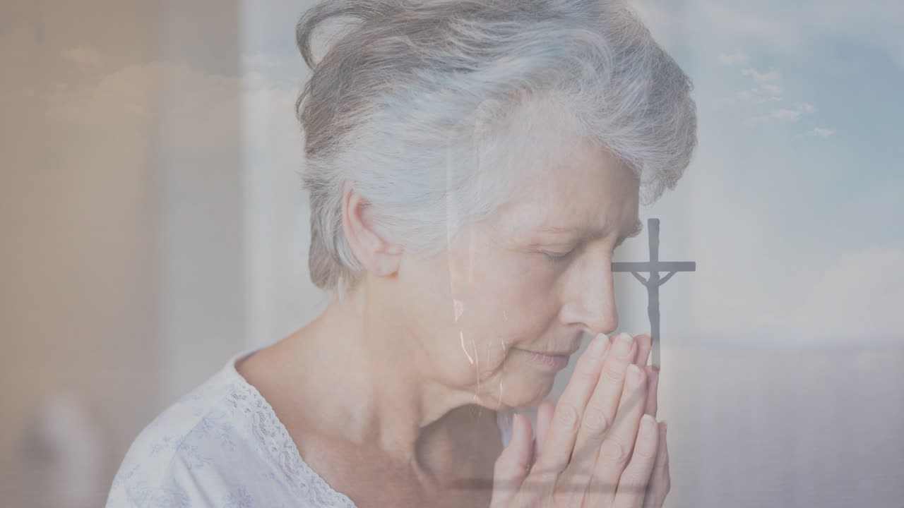 Praying with clasped hands, elderly woman in front of cross in church