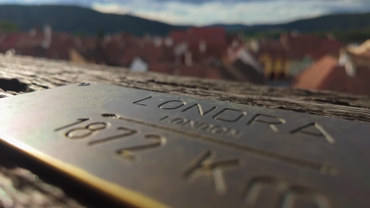 Close-up of a metal plaque indicating the distance to London, England from the Clock Tower in Sighișoara, Romania