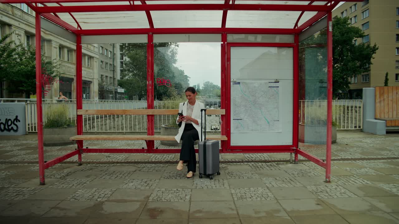 Mujer con maleta esperando en una parada de autobús