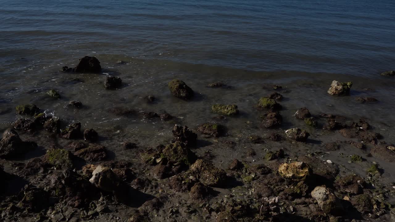 Onde che lambiscono delicatamente il bagnasciuga, cosparso di piccole rocce multicolori. È davvero una splendida scena naturale.