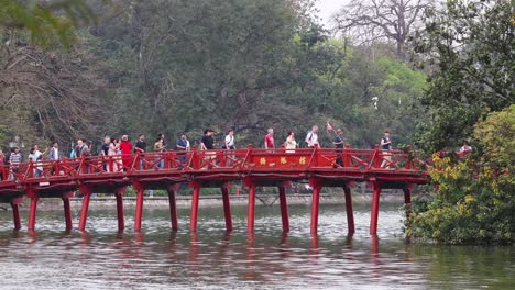 crowd crossing iconic red bridge over water