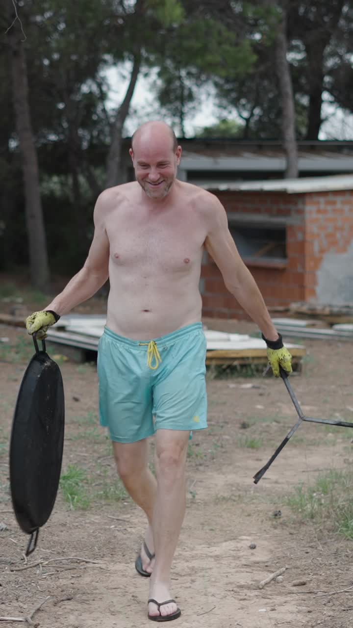 Man carrying grill and stand outdoors