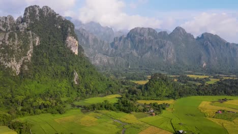 aerial view of green farming fields with soaring forested mountain landscape at vang vieng