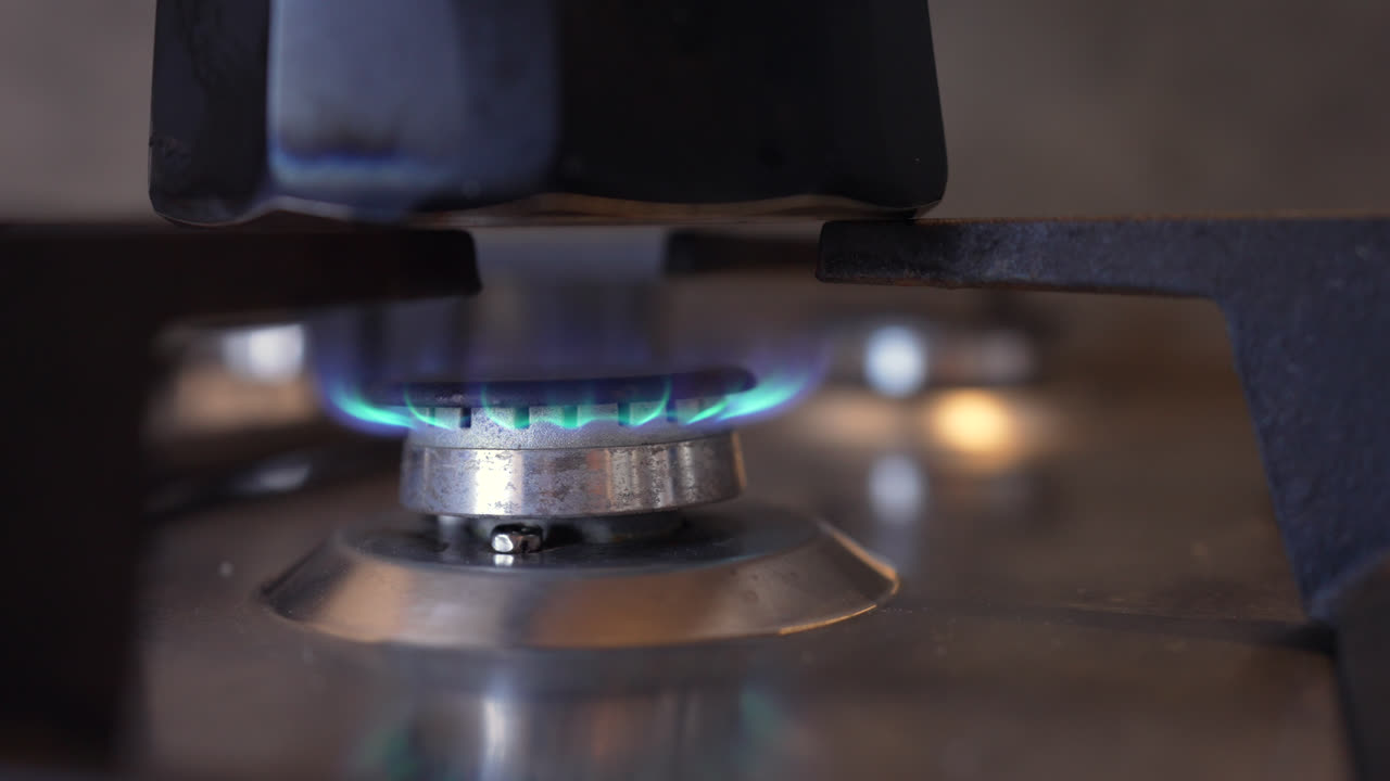 Moka pot brewing on stove, close-up of flame on gas stove, kitchen coffee at home