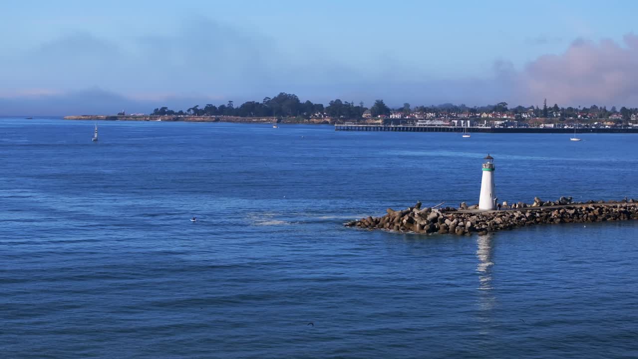 Walton Lighthouse Monterey Bay Santa Cruz California USA aerial drone scenic landscape deep blue Pacific Ocean seagull pelican birds marina harbor jetty boats morning blue sky mist fog static shot