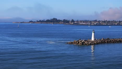 walton lighthouse monterey bay santa cruz california usa aerial drone scenic landscape deep blue pacific ocean seagull pelican birds marina harbor jetty boats morning blue sky mist fog static shot