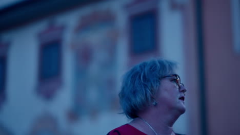 cinematic close up of an older caucasian woman looking around for direction in an old historical city at night in slow motion