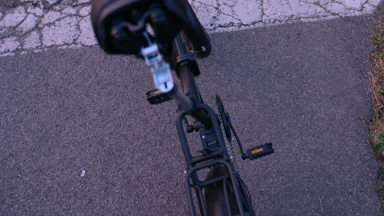 Man inserts a battery under the saddle of an electric bike, preparing it for use on a paved road. Concept of e-mobility, clean transport, and modern commuting