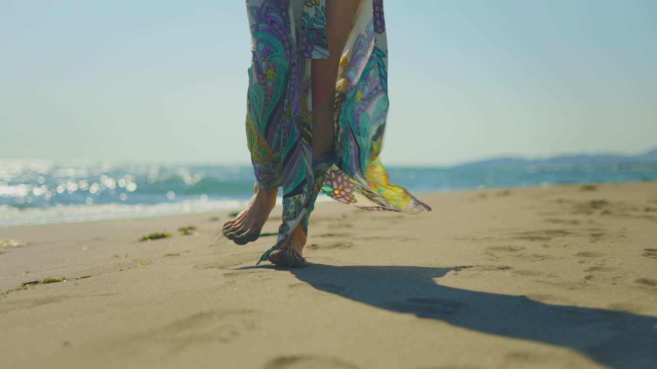 mujer caminando por la playa con un vestido floral