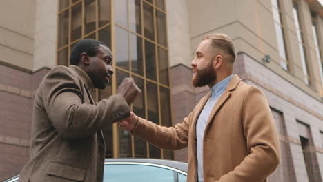 bottom view of caucasian and african american businessman in elegant clothes talking about business and arguing in the street in autumn