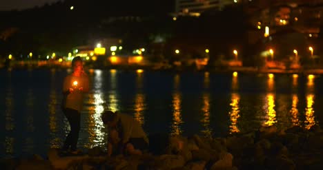 Couple-Holding-Sparklers-At-Seashore