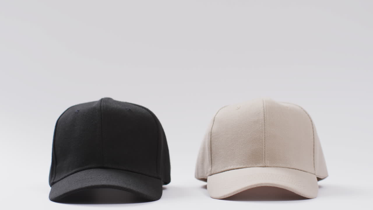 검은색과 베이지색의 야구 모자와  ⁇ 색 배경의 복사 공간의 비디오