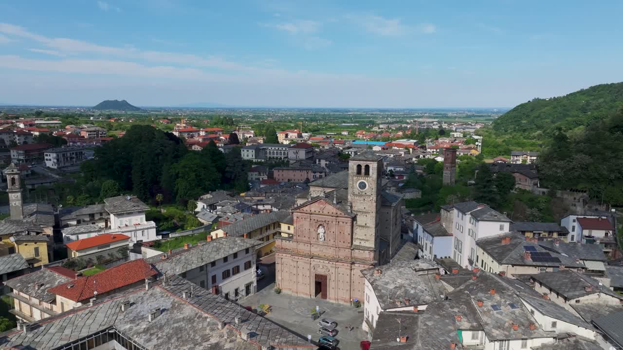 Rotating aerial drone footage showing rooftops of houses and buildings nestled in a serene valley amidst huge mountains