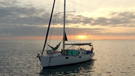 Person,-Die-Sich-Während-Der-Goldenen-Stunde-Auf-Einer-Hängematte-Auf-Einem-Segelboot-Entspannt,-Das-Im-Meer-Schwimmt