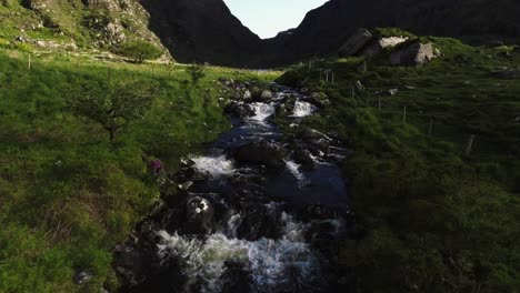 Aerial-drone-shot-of-small-river,-cliffs,-mountains,-and-nature-in-Ireland