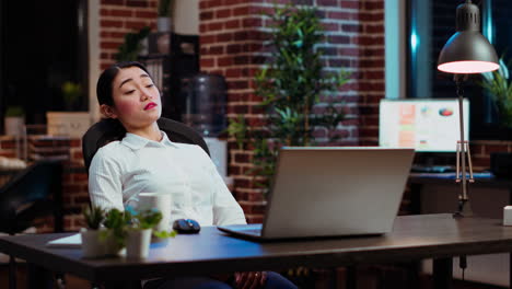 tired employee asleep on computer desk chair suddenly waking up