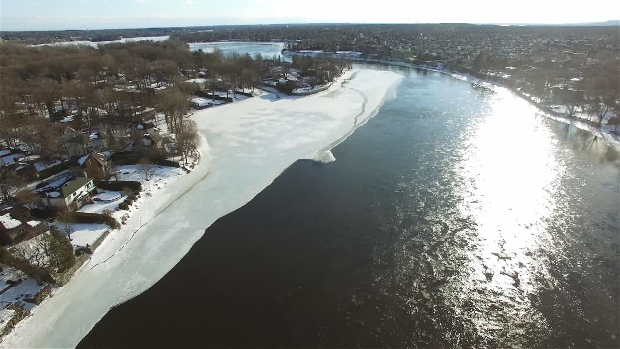 Slow-moving drone shot on a sunny day over a lake with houses surrounding it
