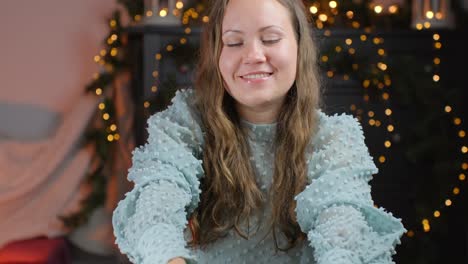 woman gifting a wrapped present with a joyful smile in a cozy home setting by the fireplace in the background