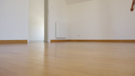 young woman walking on empty wooden apartment floor, low angle view