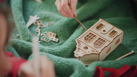mujer recortada montando un ornamento de casa de cartón en el suelo durante la navidad