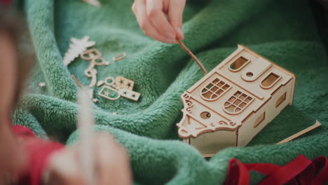 cropped woman assembling cardboard house ornament on floor during christmas