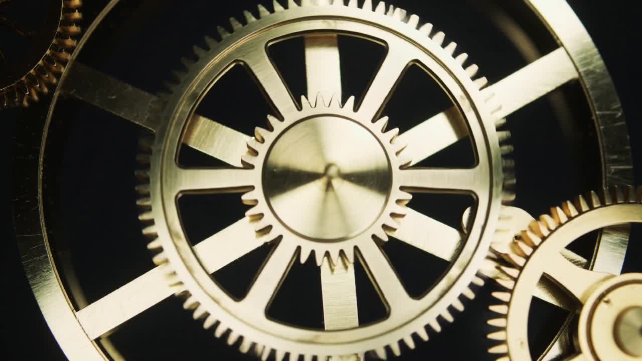 Driving axle turning large brass spur gear meshing with right pinion, transmitting motion in macro