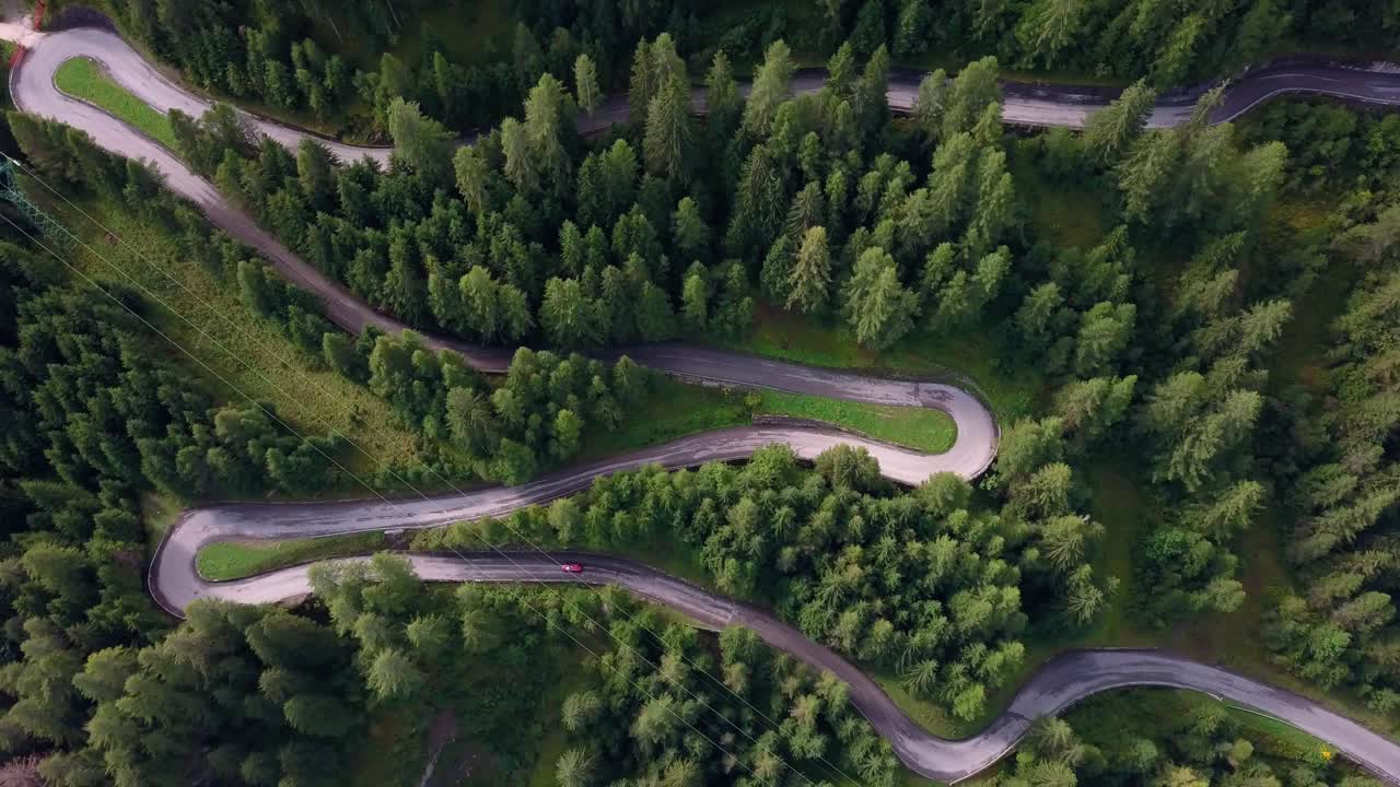 camino sinuoso en el parque de montaña dolomita norte de italia con coche rojo avanzando, vista aérea de drones con rotación
