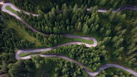 Camino-Sinuoso-En-El-Parque-Montañoso-Dolomita-Del-Norte-De-Italia-Con-Coche-Rojo-Avanzando,-Vista-Aérea-De-Drones-Con-Rotación