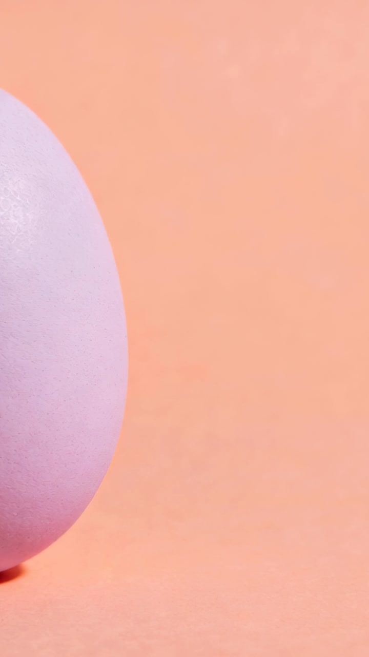 Mostrando un uovo rosa lavanda pastello su un tavolo color pesca con una morbida lucentezza e una piccola ombra, con spazio per il testo.