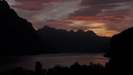 dramatic sunset over silhouette of mountains and lake at walensee, switzerland
