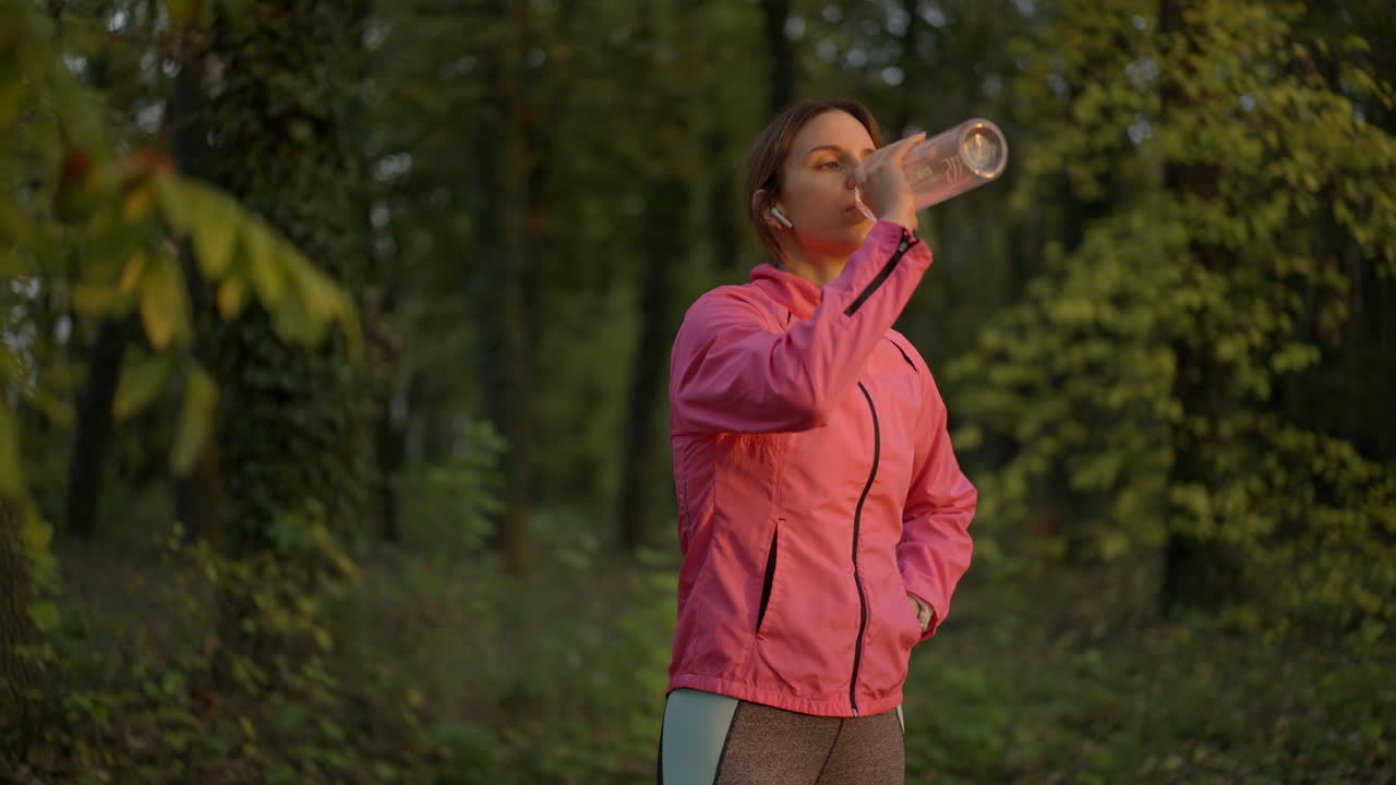 Woman taking a water break while exercising in a forest