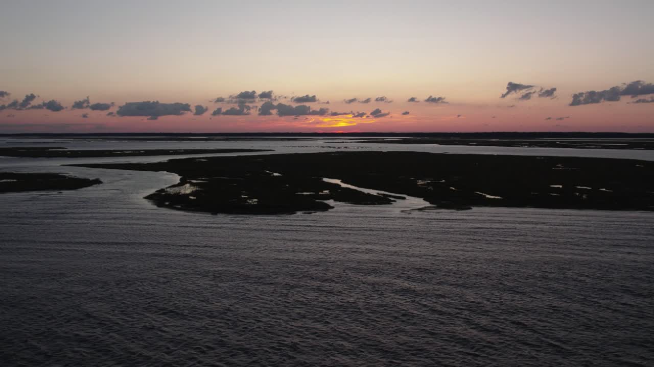 brillo rojo de la puesta de sol en el horizonte con humedales y mareas oceánicas extendidas a través del horizonte, isla de chincoteague virginia, cámara lenta