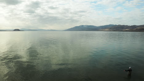 aerial flyby of fly fisherman casting at scenic shimmering pyramid lake in nevada, usa