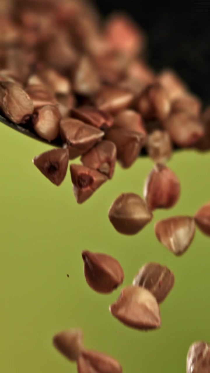 Buckwheat Grains Falling in Slow Motion on Green Background