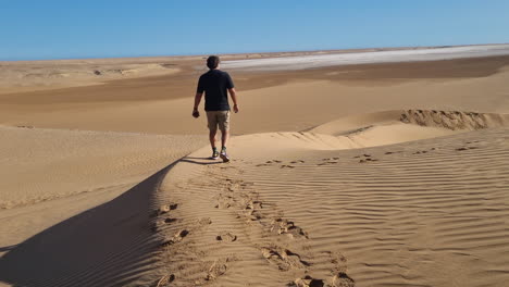 Man-walking-in-the-Sahara-desert-and-leaving-footprints