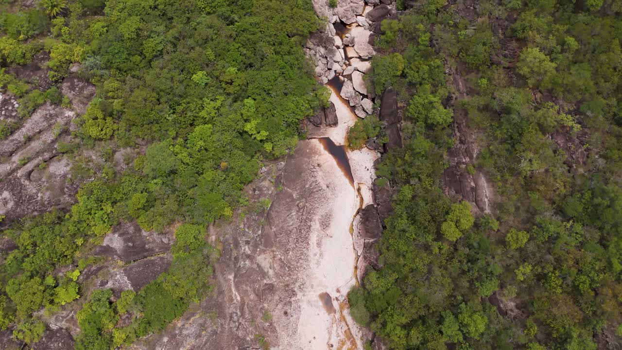 Drone shot of a rocky surface through a green landscape