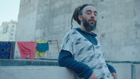 portrait of handsome man with dreadlocks and beard on urban rooftop