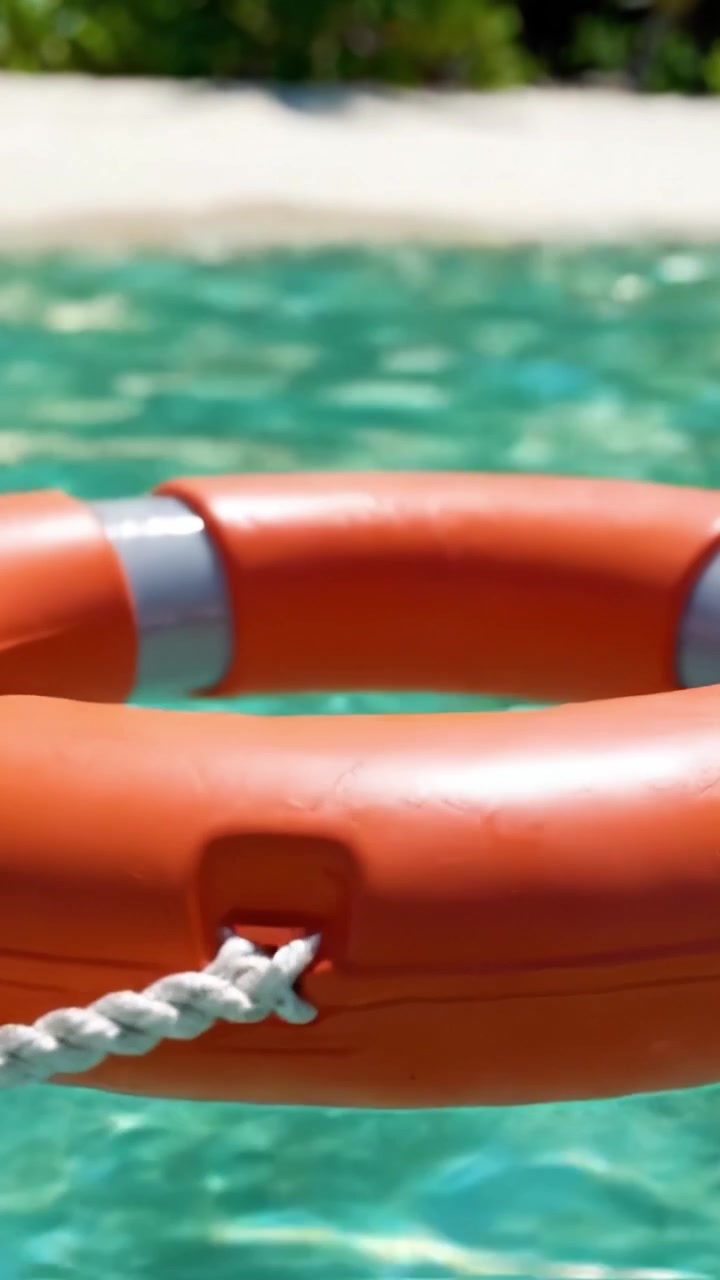 A Durable Lifebuoy Floating Calmly in Pristine Turquoise Waters with a Serene Sandy Beach in the Background, Perfect for Safety and Relaxation