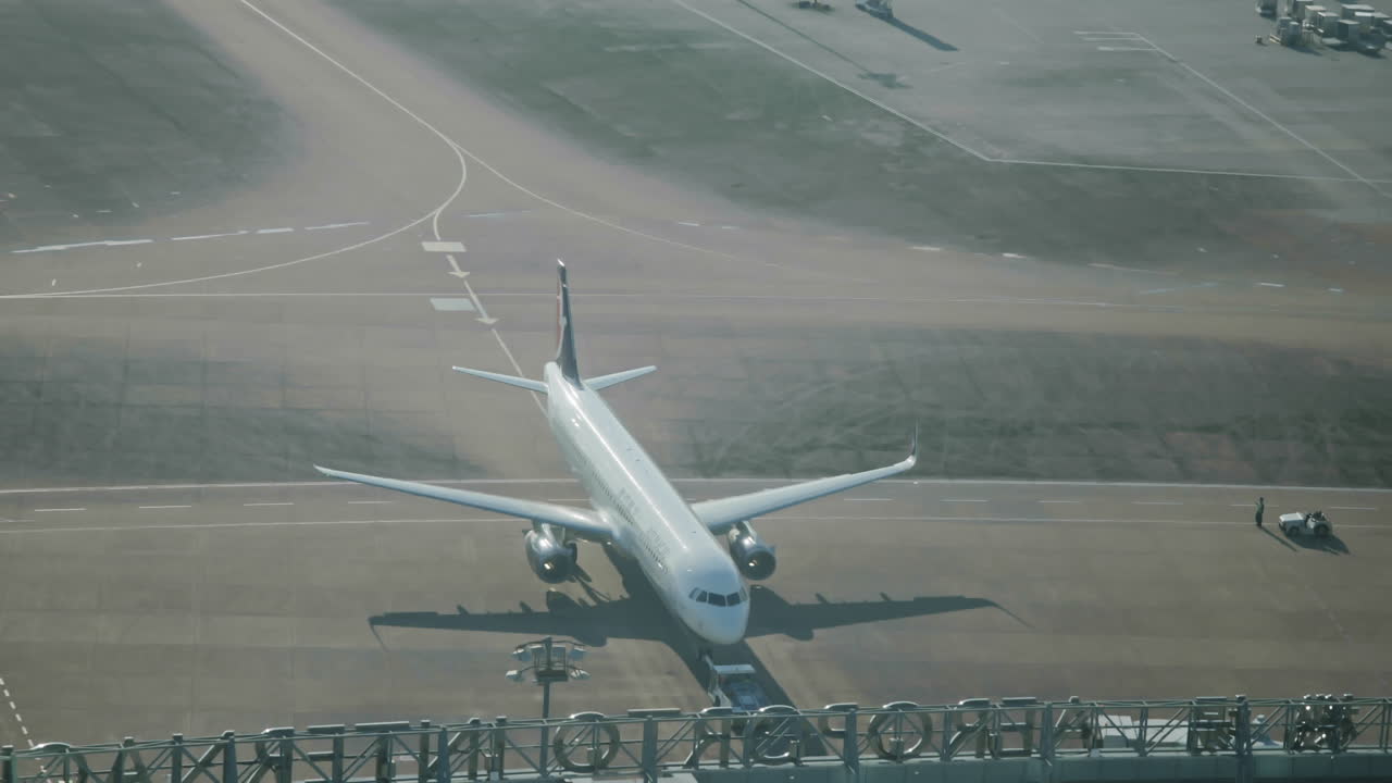 地上作業員がいる空港の駐機場に駐機された飛行機