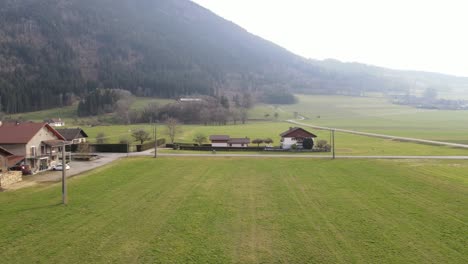 A-cyclist-riding-on-an-open-road-surrounded-by-fields-with-green-grass-and-village-houses