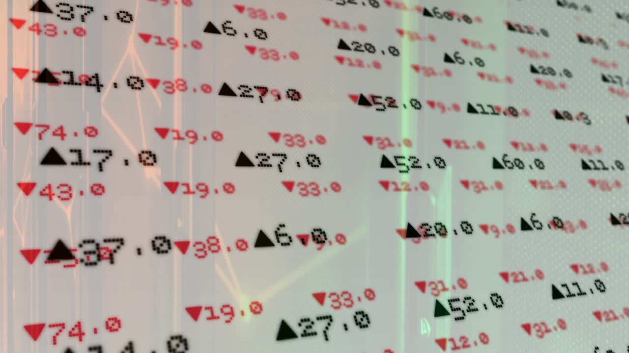 Camera panning revealing panel showing red down and black up triangles across numeric clusters