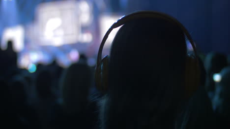 Frau-In-Der-Menge-Beim-Konzert-Setzt-Kopfhörer-Auf